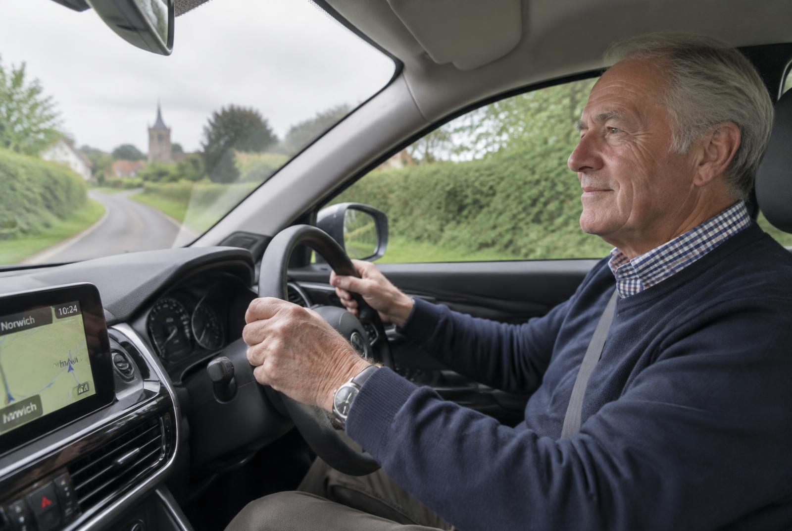 Older man driving calmly along a country road
